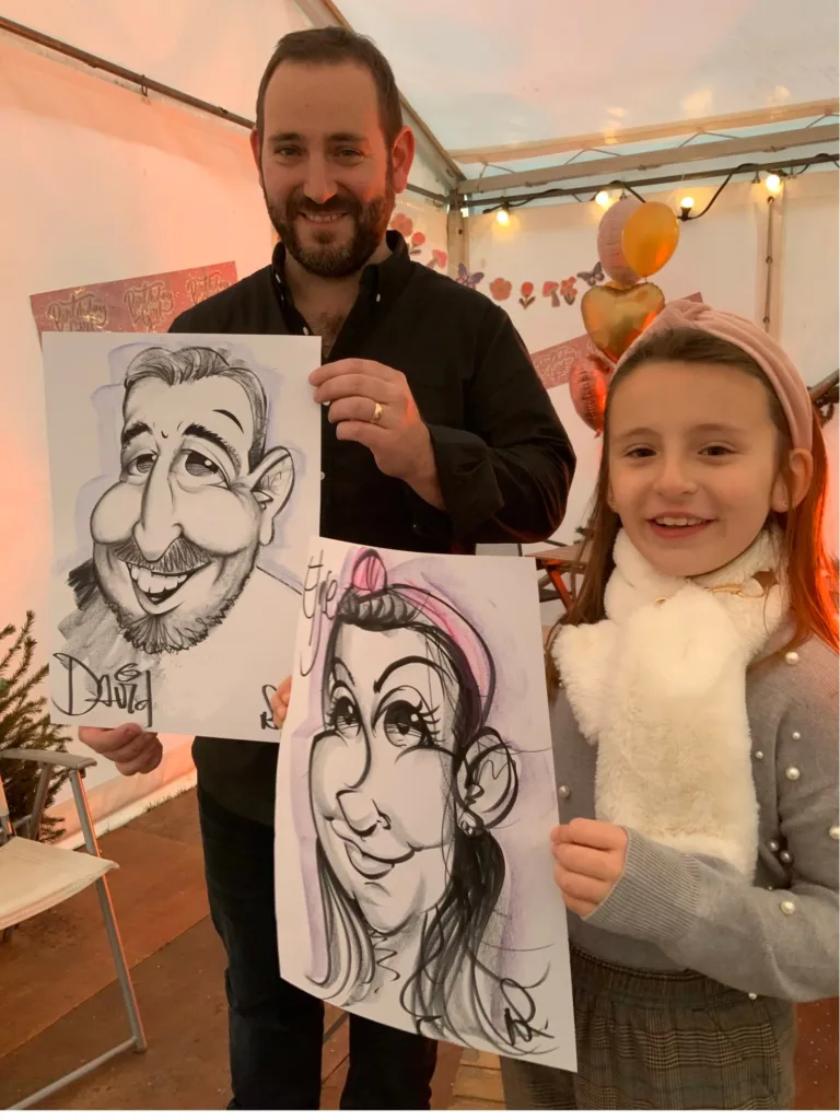 A dad and his daughter holding their caricature portraits at a party in Newry, N.I.